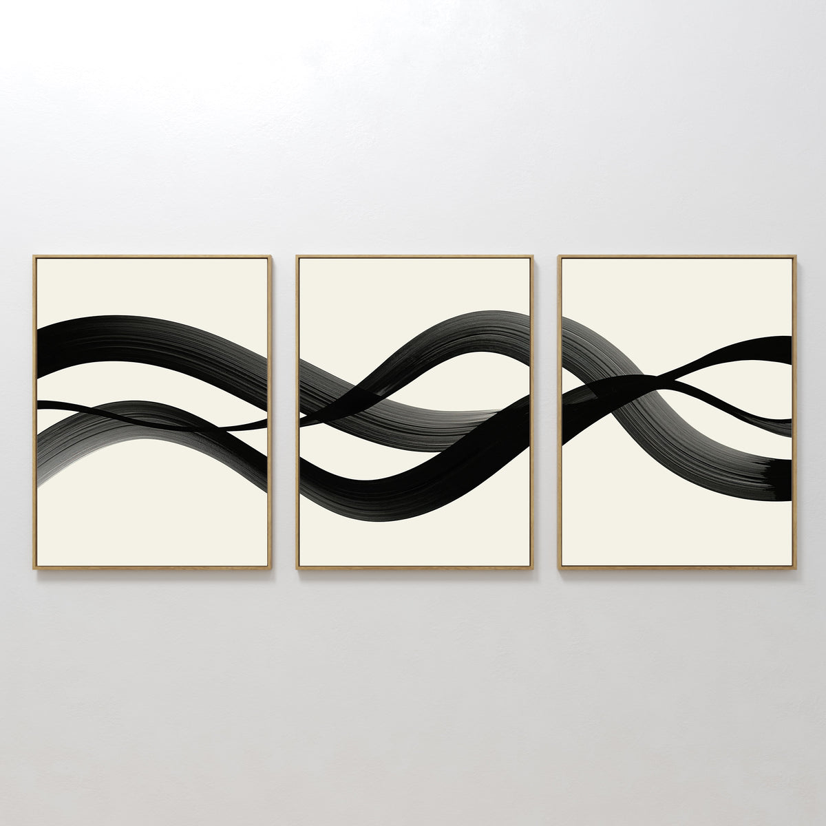 The Fluid Curves Set of 3 showcases framed abstract prints with bold black wavy brushstrokes on white backgrounds, forming a continuous, modern wall art pattern when displayed side by side.