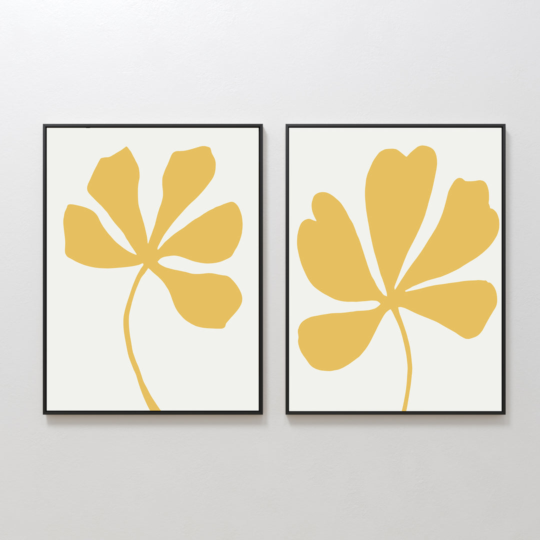 The Sunleaf Silhouettes Set of 2 features framed minimalist wall art prints with abstract yellow floral shapes and multiple petals on a white background, shown side by side for a contemporary look.