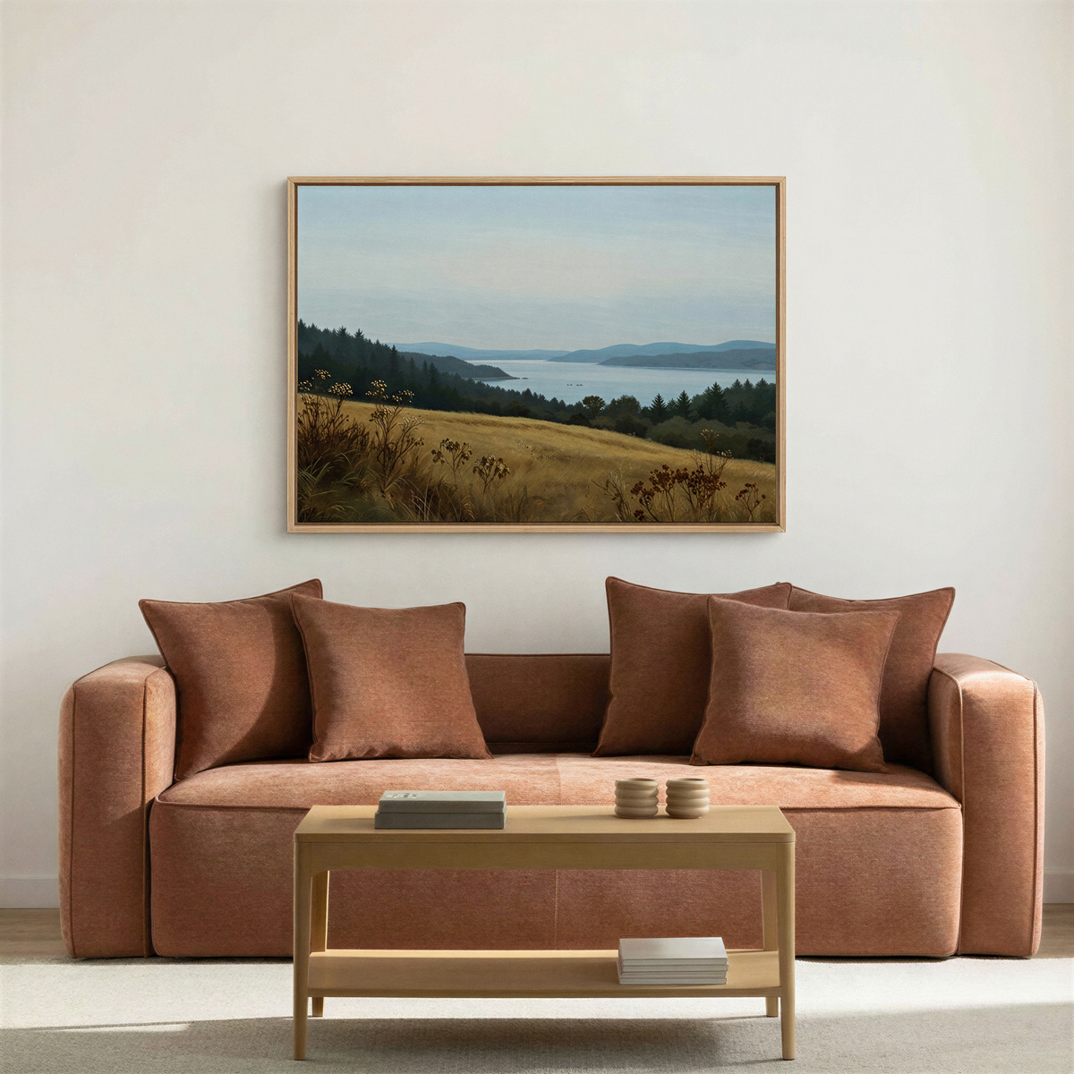 A cozy living room with a rust-colored sofa, four matching pillows, minimalist "Northern Silence Canvas Art" of hills and sky above the sofa, and a light wooden coffee table with books—perfect for stylish yet simple decor.