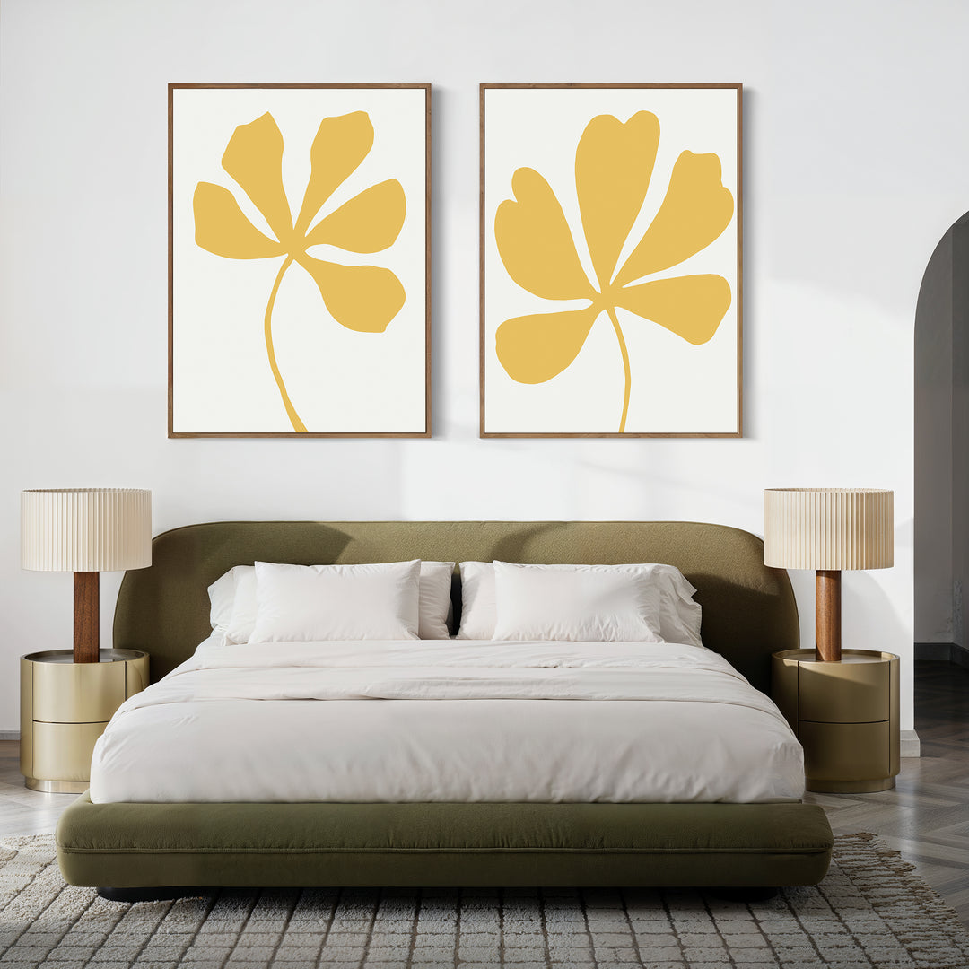 A modern bedroom with an olive green bed, white bedding, beige nightstands with matching lamps, and the Sunleaf Silhouettes Set of 2 wall art featuring yellow abstract leaves above the headboard for a contemporary touch.