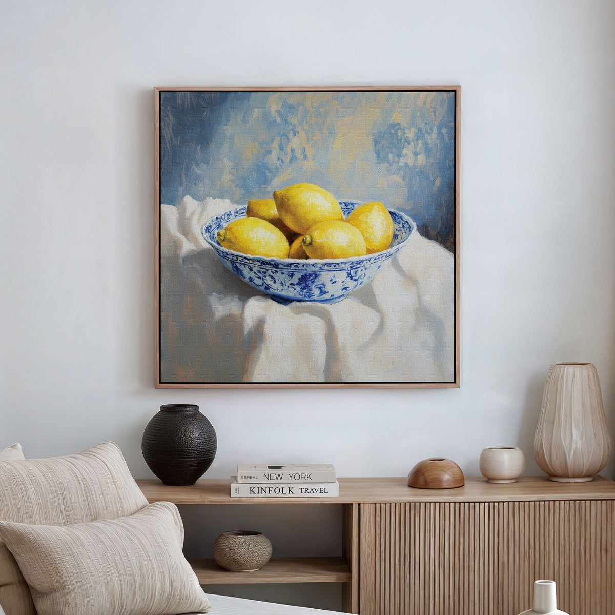 The Golden Fruit Canvas Art hangs above a wooden sideboard with ceramic vases, a candle, and books, bringing charming rustic wall art to a minimalist living space with neutral tones.