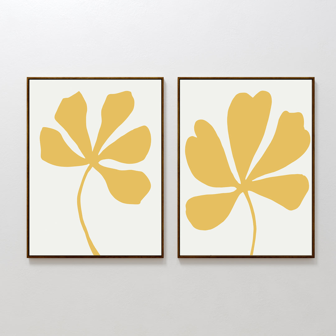 The Sunleaf Silhouettes Set of 2 features minimalist framed prints with abstract yellow botanical shapes on white, displayed side by side to add contemporary floral style to any plain wall.