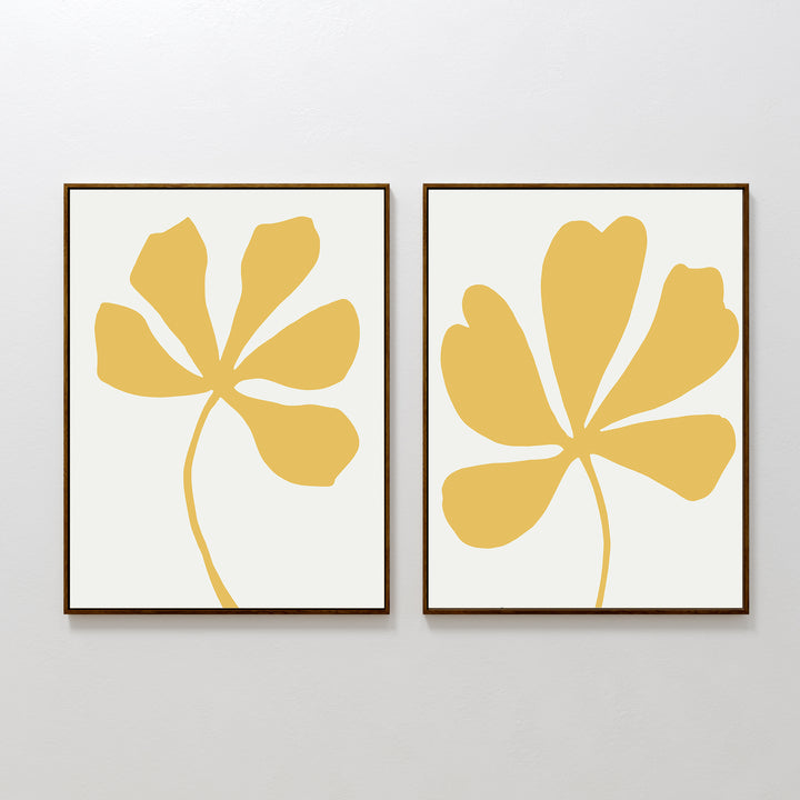 The Sunleaf Silhouettes Set of 2 features minimalist framed prints with abstract yellow botanical shapes on white, displayed side by side to add contemporary floral style to any plain wall.