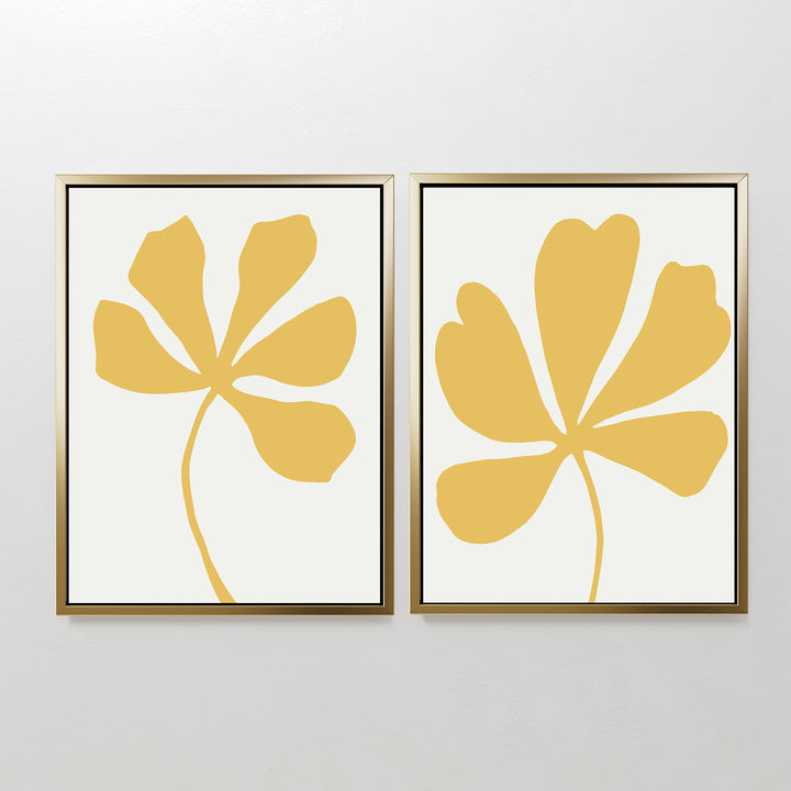 Sunleaf Silhouettes Set of 2: Framed minimalist wall art prints with abstract yellow floral shapes and thick petals on white, displayed side by side for a bold touch of contemporary floral design.