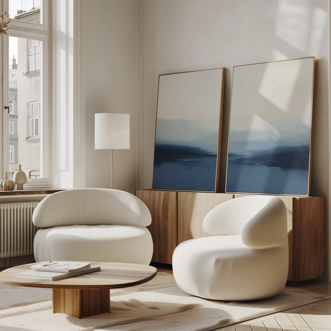 A room with white chairs and a table features minimalist decor, complemented by the Blue Valley Mist Set of 2 wall art prints.
