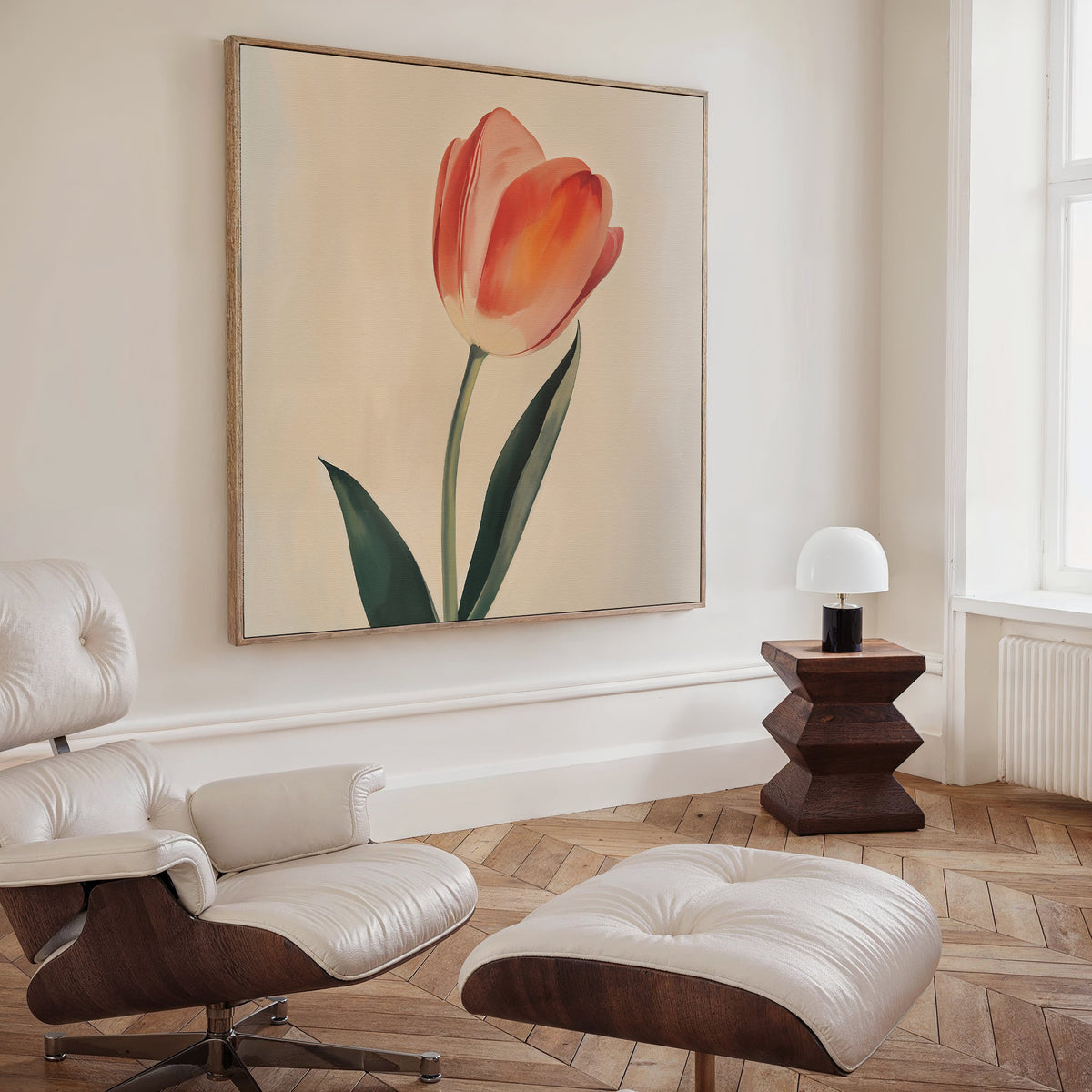 A modern living room features a white lounge chair and ottoman, wooden side table with lamp, and Blush Tulip Canvas Art as the centerpiece. Light wood floors and a window add natural light to this minimalist setting.