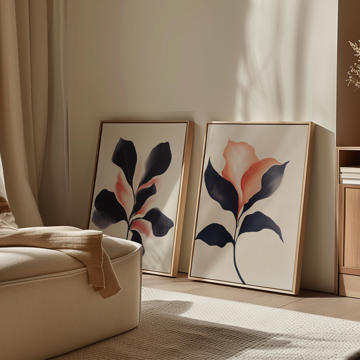 The Blush & Shadow Set of 2 framed botanical wall art prints with abstract floral designs rests on the floor against a sunlit, neutral-toned living room wall with soft furnishings.
