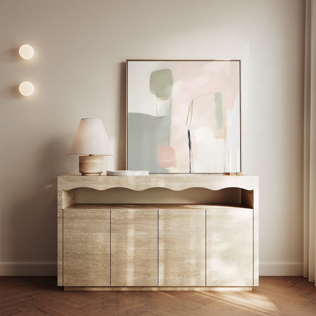 A minimalist beige console table with a wavy edge, a lamp, two candlesticks, and the Blushed Horizon Canvas Art leaning against a light wall. Two round wall lights and sheer curtains complete the calm, modern decor.