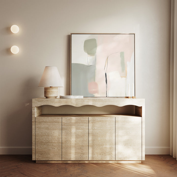 A minimalist beige console table with a wavy edge, a lamp, two candlesticks, and the Blushed Horizon Canvas Art leaning against a light wall. Two round wall lights and sheer curtains complete the calm, modern decor.