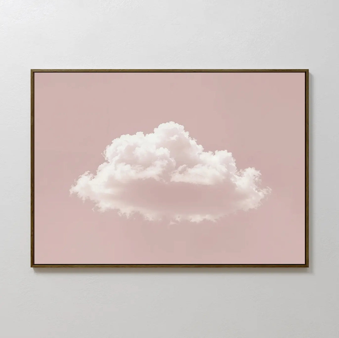 The Blushing Sky Canvas Art features a fluffy white cloud centered on a soft pink background—ideal for minimalist decor or as calming bedroom wall art. Display it on a light-colored wall for a serene touch.