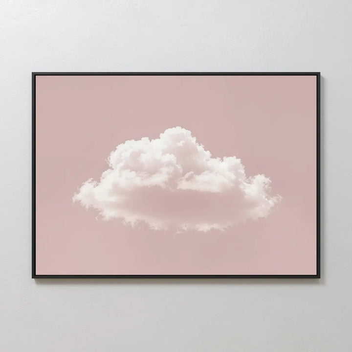 The Blushing Sky Canvas Art features a fluffy white cloud on a soft pink background, displayed on a light gray wall—an ideal minimalist decor accent and charming wall art print.