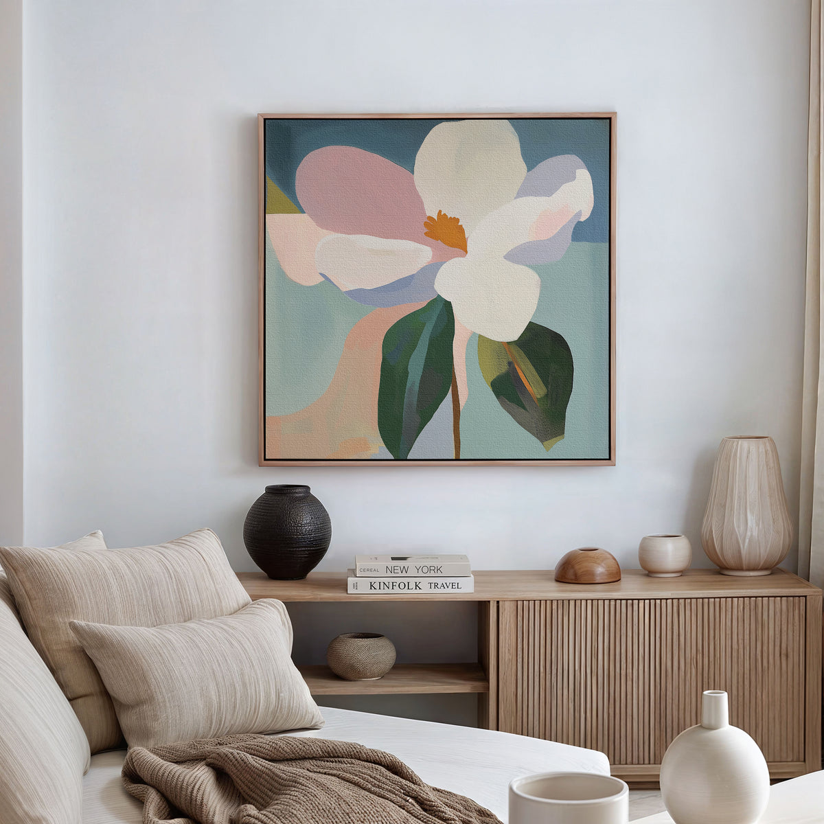 A cozy, neutral-toned living room exudes modern elegance, showcasing the Bold Bloom Canvas Art above a wooden sideboard adorned with vases, books, and ceramics. A light sofa with cushions is placed in the foreground.