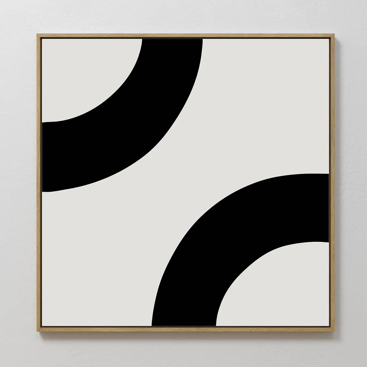 Bold Orbit Canvas Art features two thick black curved bands on a white background, framed in light wood. Mounted on a white wall, it’s ideal minimalist abstract wall art for modern interiors.