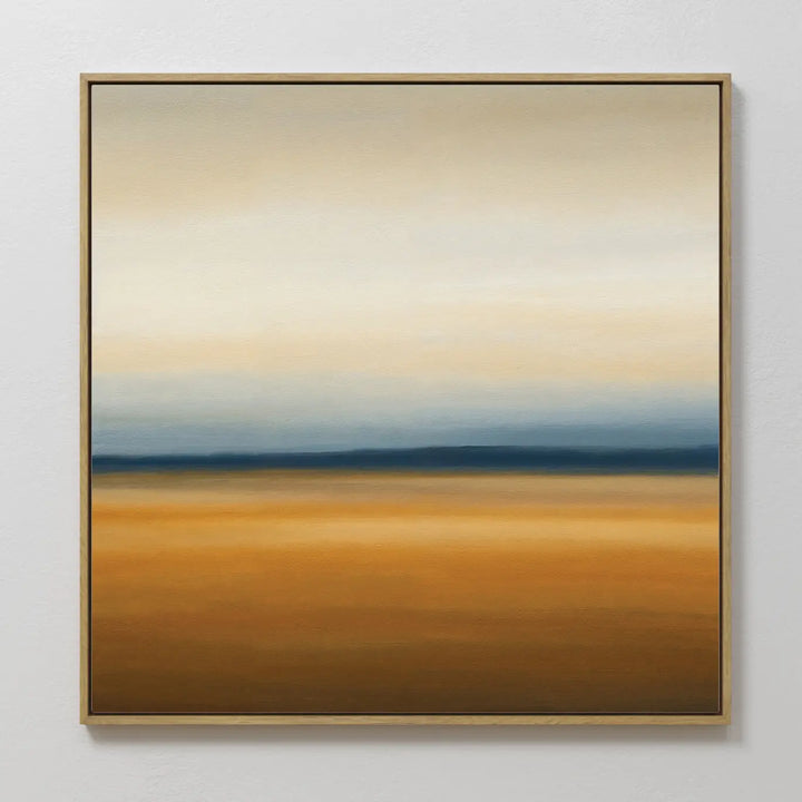 Caramel Plains Canvas Art features warm golden-brown layers, a blue-gray band, and soft white-beige tones, all framed in a slim golden frame—an ideal abstract wall art piece for modern bedroom decor.