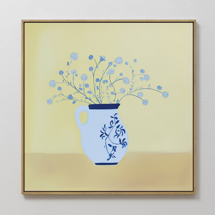 The Cerulean Petals Canvas Art features a blue and white floral vase with delicate round white flowers against a soft yellow background. This minimalist, framed wall decor is perfect for adding elegance to any white wall.