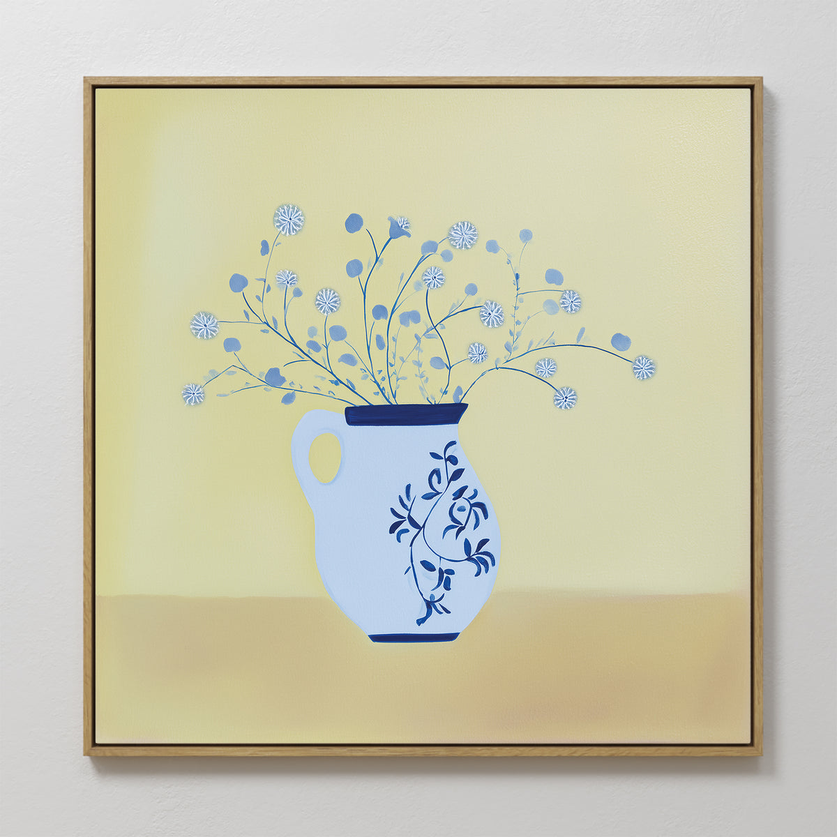 The Cerulean Petals Canvas Art features a blue and white floral vase with delicate round white flowers against a soft yellow background. This minimalist, framed wall decor is perfect for adding elegance to any white wall.