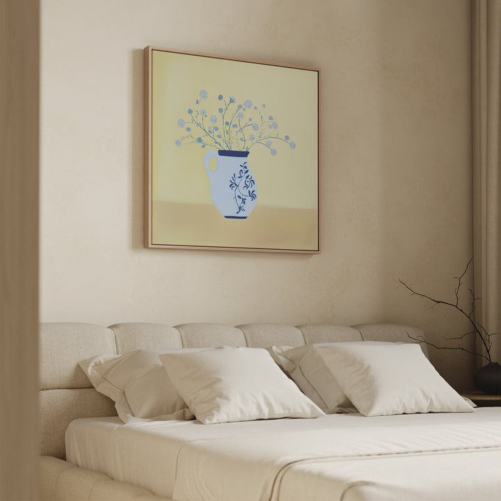 A minimalist bedroom features a beige upholstered bed, white pillows, and the Cerulean Petals Canvas Art above the headboard, displaying blue flowers in a vase set against a yellow background.