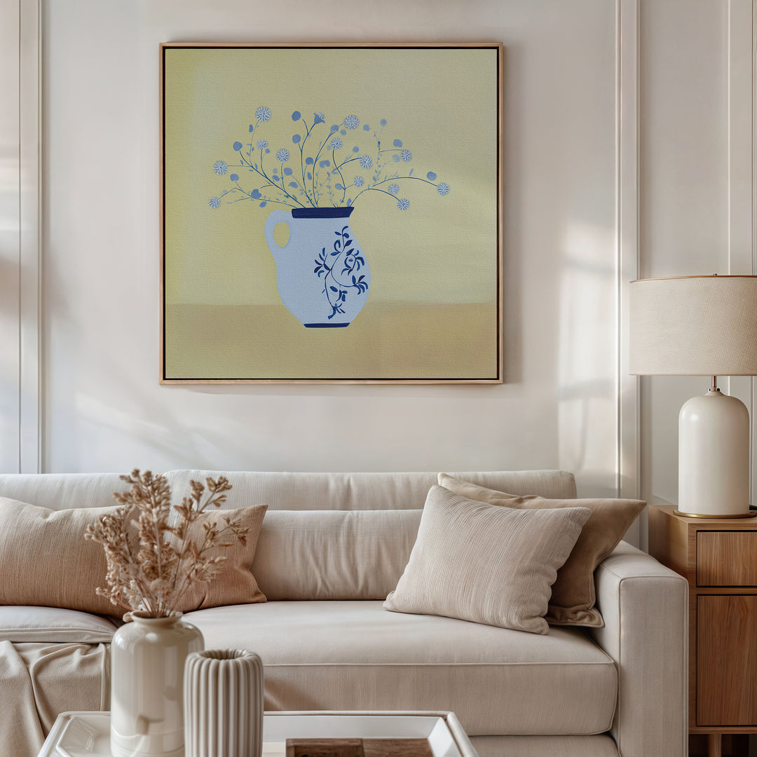 A neutral-toned living room features a white sofa, beige pillows, and a lamp. Above the sofa, Cerulean Petals Canvas Art adds elegance while dried flowers and decorative objects adorn the coffee table.