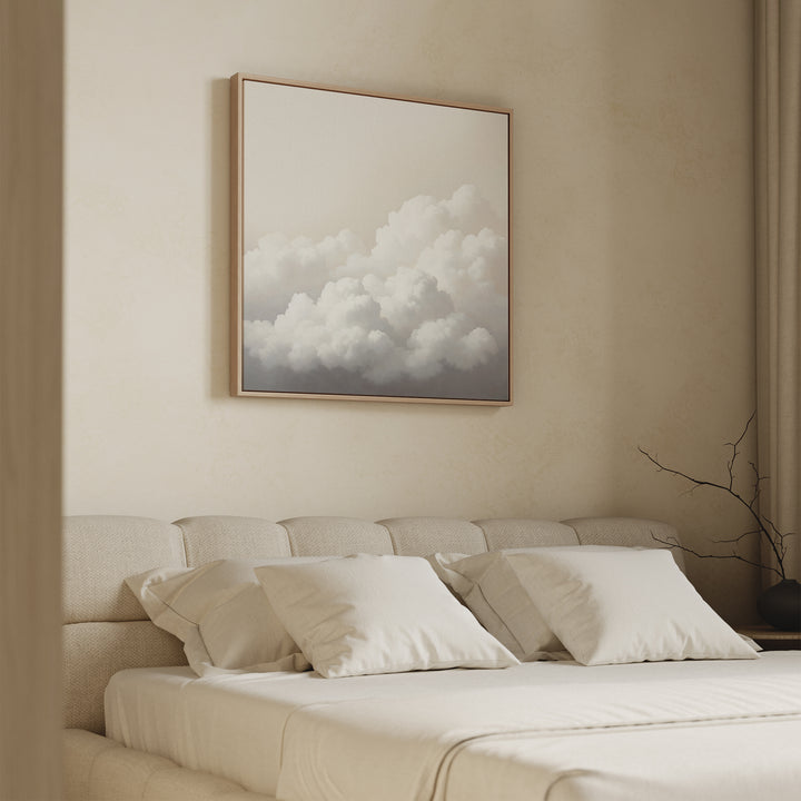 A minimalist bedroom with a beige bed and four pillows, featuring calming decor and the Cloud Reverie Canvas Art above the headboard. The space has light walls and a bare branch displayed in a vase on the right side.