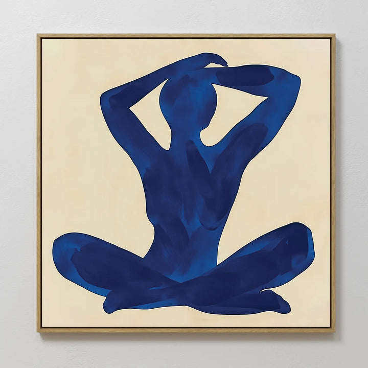 Cobalt Figure Canvas Art: A minimalist canvas with a blue silhouette of a seated figure, legs crossed and arms raised, set on a light beige background in a square frame—perfect for modern wall art enthusiasts.