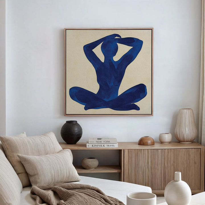 A modern living room with neutral tones, a beige sofa, decorative books and vases on a wooden cabinet, and the Cobalt Figure Canvas Art framed above the seating area as minimalist modern wall decor.