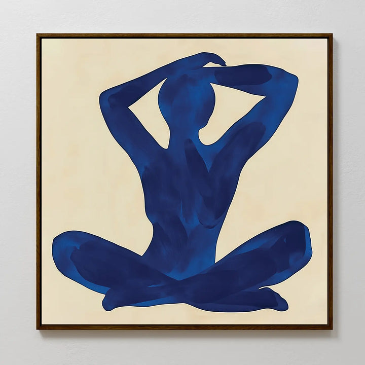 Cobalt Figure Canvas Art: A minimalist canvas featuring a blue seated silhouette with raised arms on a beige background, set in a dark wooden frame—a striking modern wall art piece.