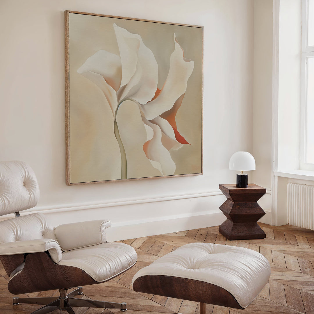 A modern, minimalist living room features a white lounge chair and ottoman, wooden side table with lamp, Delicate Bloom Abstract Canvas Art on the wall, plus a light wood herringbone floor and large window for modern elegance.