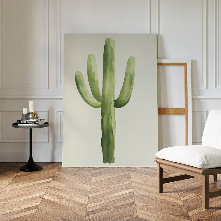 The Desert Cactus Canvas Art leans against a white wall in a modern room with herringbone floors, beside an empty frame, white cushioned chair, and black side table—an ideal piece for minimalist decor.