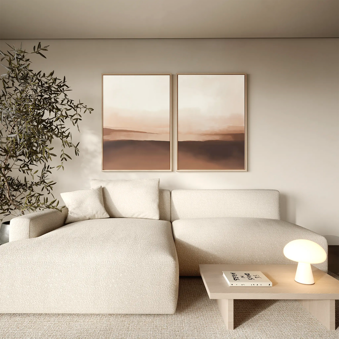A modern living room with a beige sectional sofa, a small wooden coffee table, and the Desert Landscape Set of 2 minimalist prints on the wall, featuring neutral tones and a leafy plant in the corner for a calm, serene atmosphere.