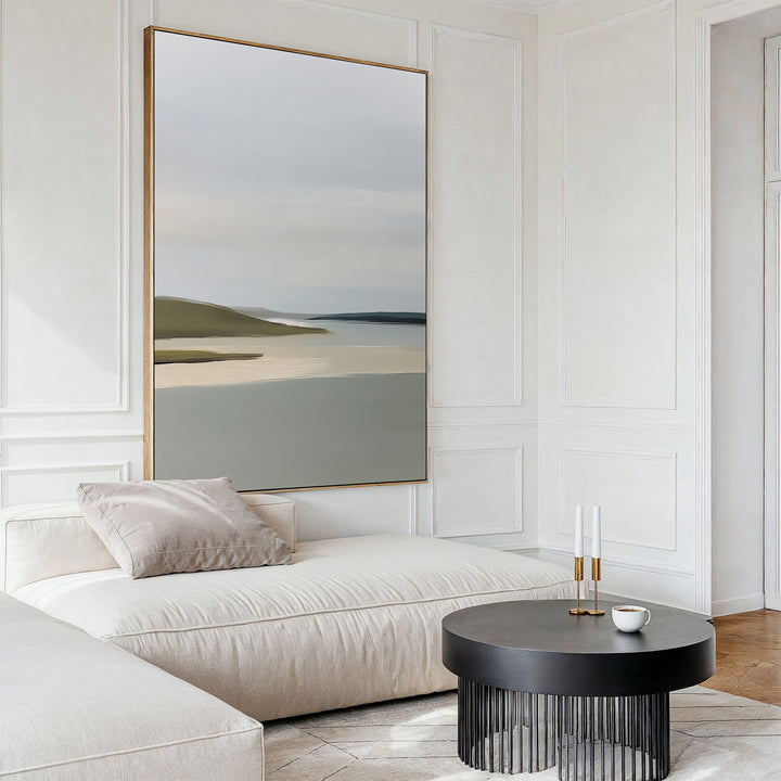 A modern living room showcases the Distant Shores Canvas Art, a minimalist abstract landscape above a white chaise lounge with beige cushion and a round black coffee table, set against white paneled walls and wooden flooring.