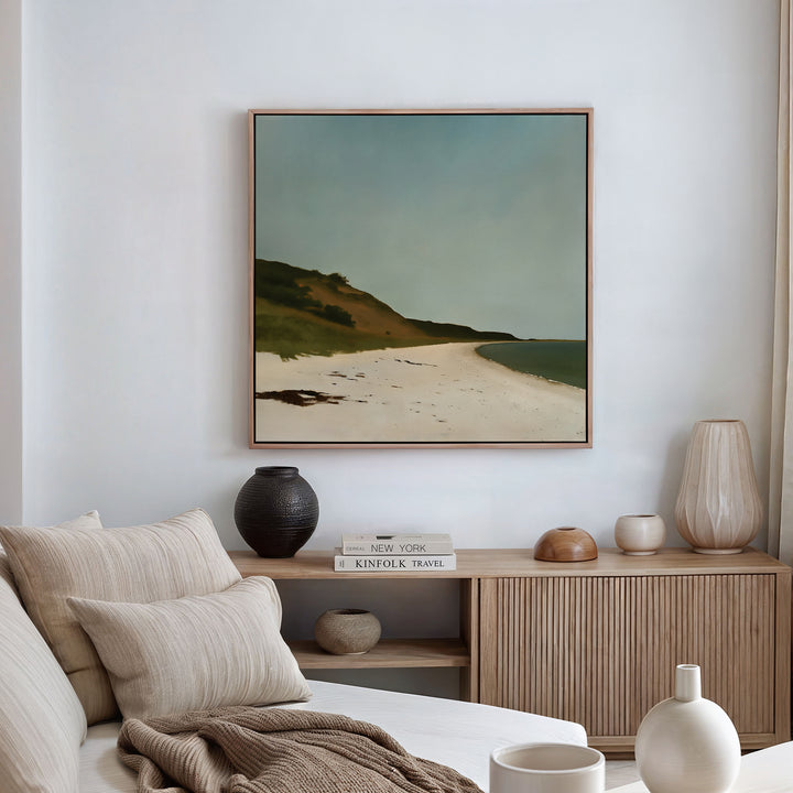 A cozy living room with a beige sofa, neutral cushions, a wooden sideboard with decor, and large wall art—Drift Shore Canvas Art—hanging on the wall for a serene beach vibe.