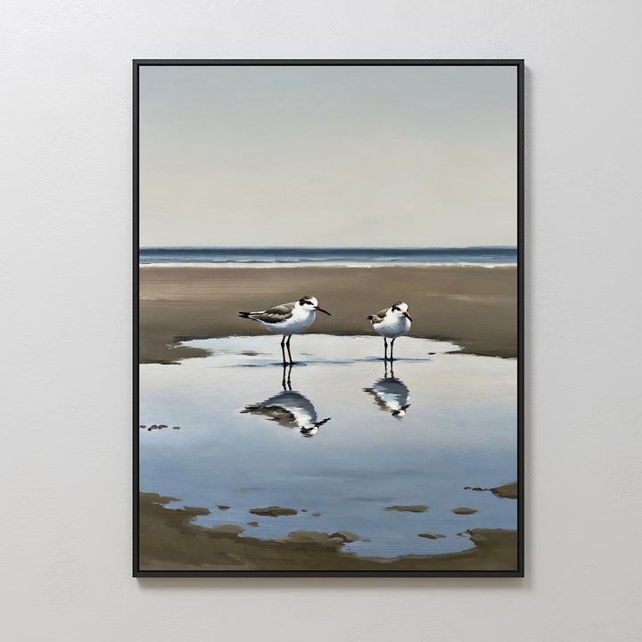 Drifted Calm Canvas Art features a minimalist framed painting of two shorebirds standing in a shallow puddle on a sandy beach, their reflections shimmering—ideal wall art for contemporary interiors and calm coastal spaces.
