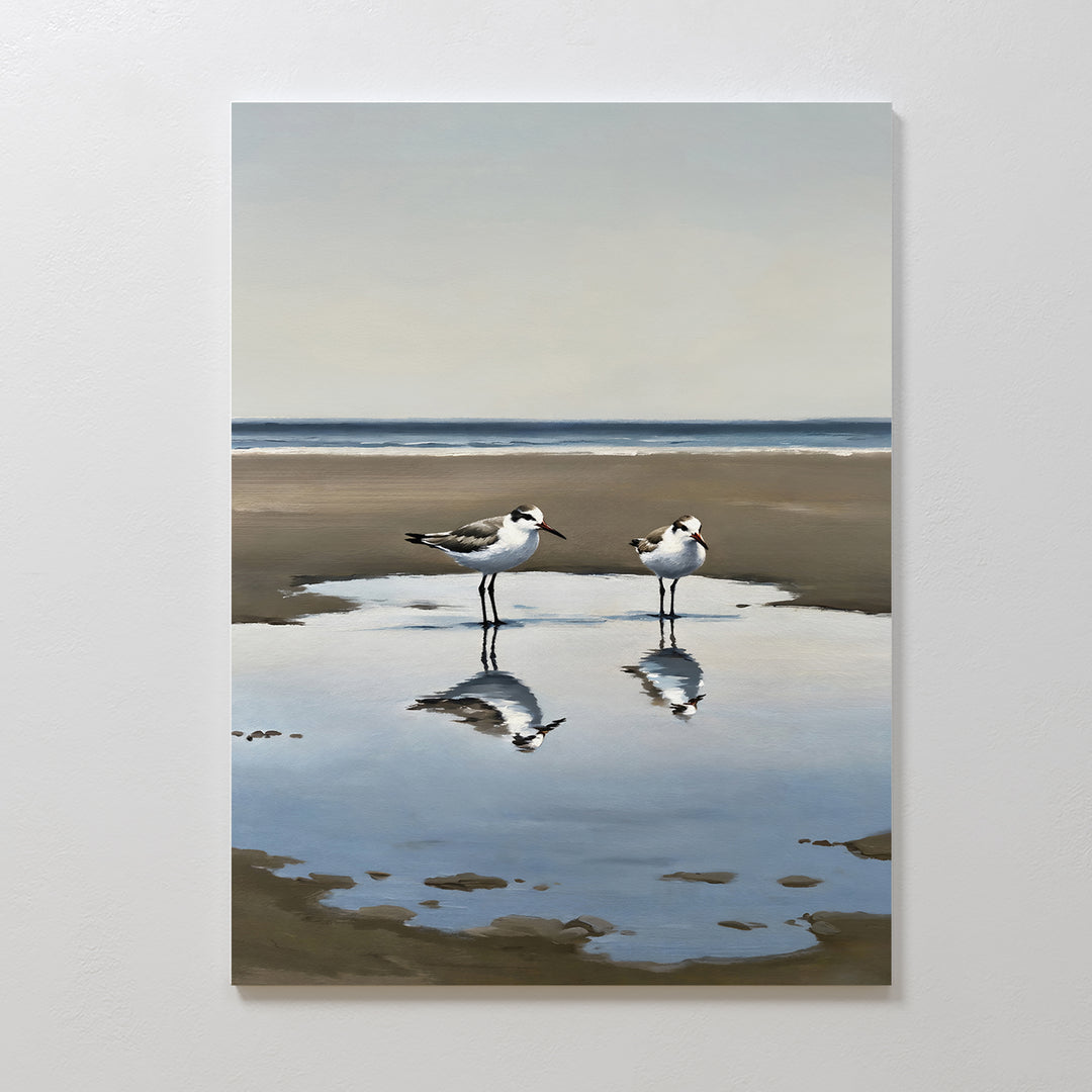 Drifted Calm Canvas Art features two shorebirds by a shallow pool on a sandy beach, their reflections captured against a soft ocean and sky—an ideal minimalist piece to add serene beauty to contemporary interiors.