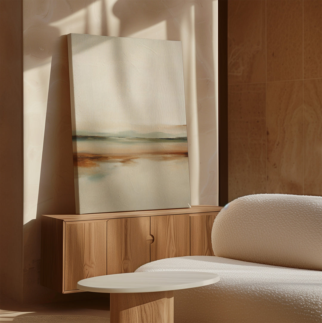 A minimalist living room with a light wood sideboard, the Earthly Hues Abstract Canvas Art leaning against the wall, a white textured sofa, and a round white coffee table, all bathed in natural sunlight.