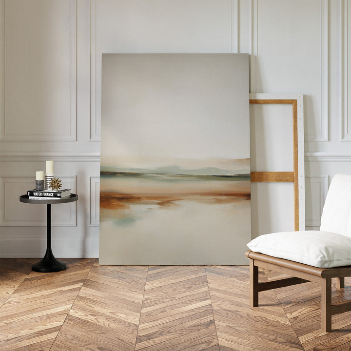 A minimal, modern living room decor with herringbone wood floors, a white cushioned chair, black side table with candles and books, and the Earthly Hues Abstract Canvas Art—a striking abstract landscape—leaning against the wall.