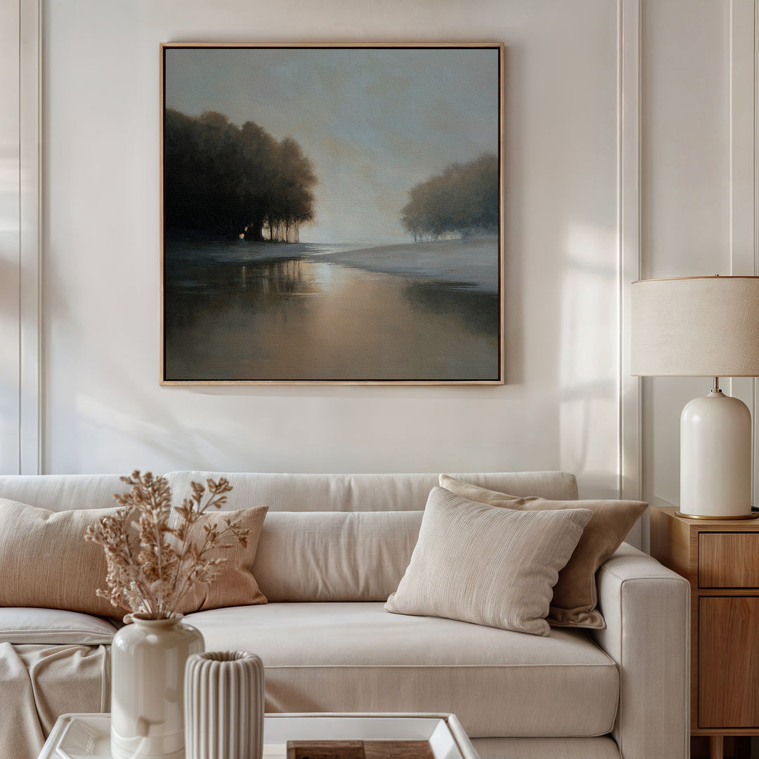 A cozy living room features a beige sofa, neutral pillows, side table with lamp, dried flowers in a vase, and the Ember Shore Canvas Art above the sofa, completing the inviting decor.