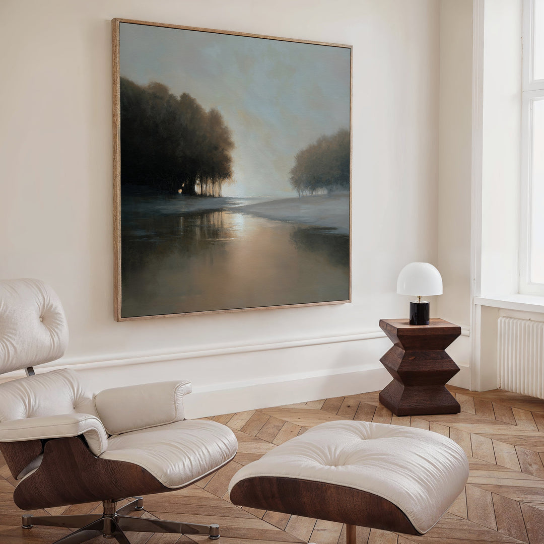 A modern living room with a white leather lounge chair and ottoman, a dark wood side table with a white lamp, and the Ember Shore Canvas Art creates refined living room decor.