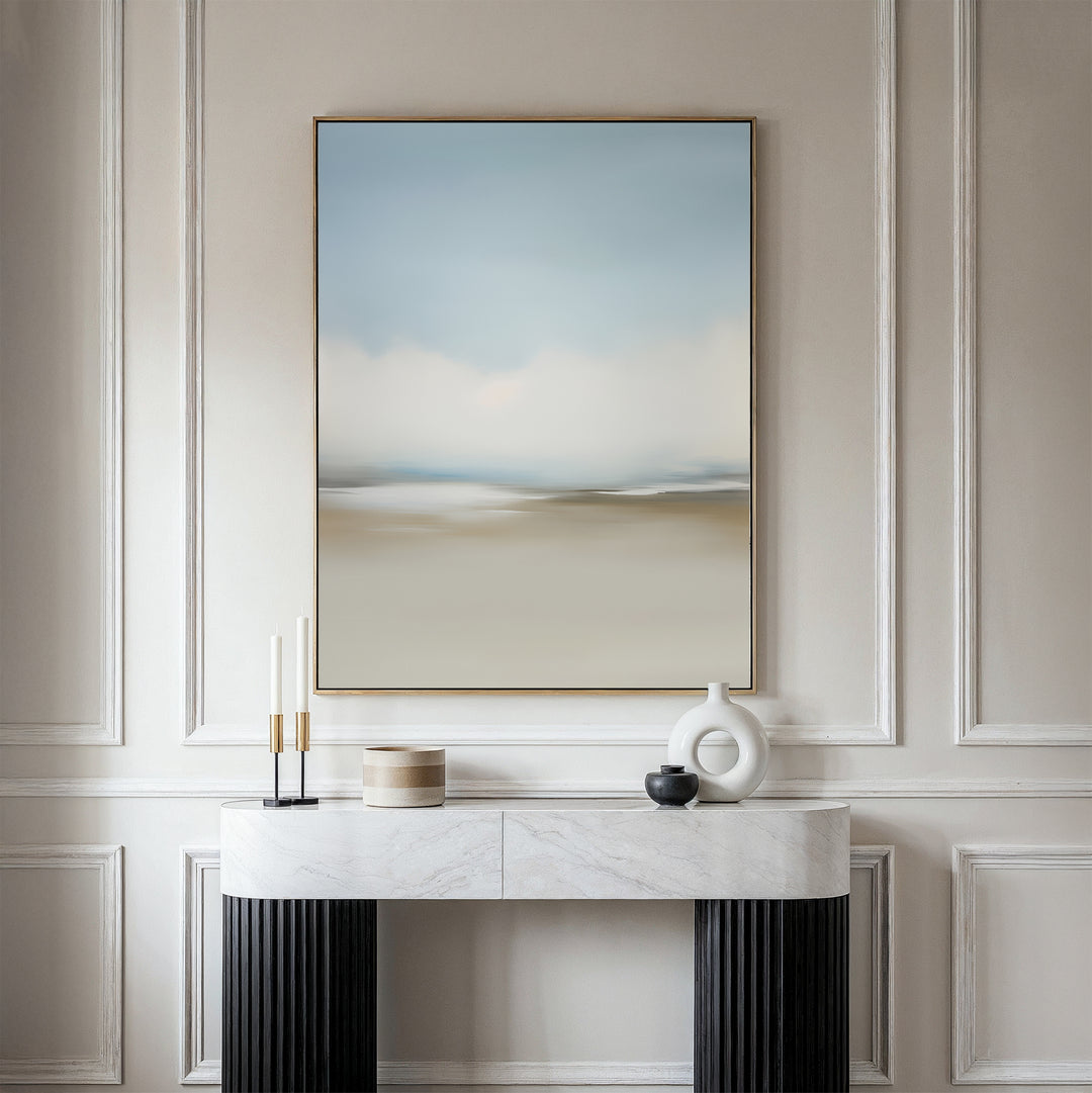 The Faded Silence Canvas Art in soft blue and beige tones hangs on a white wall above a marble console table, styled with minimalist decor such as candles, a round box, and modern ceramic vases.