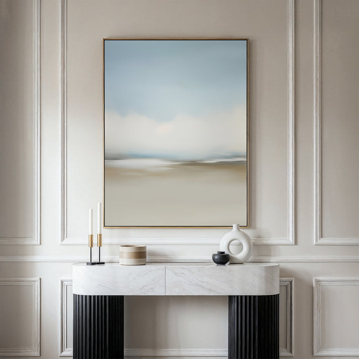 The Faded Silence Canvas Art in soft blue and beige tones hangs on a white wall above a marble console table, styled with minimalist decor such as candles, a round box, and modern ceramic vases.
