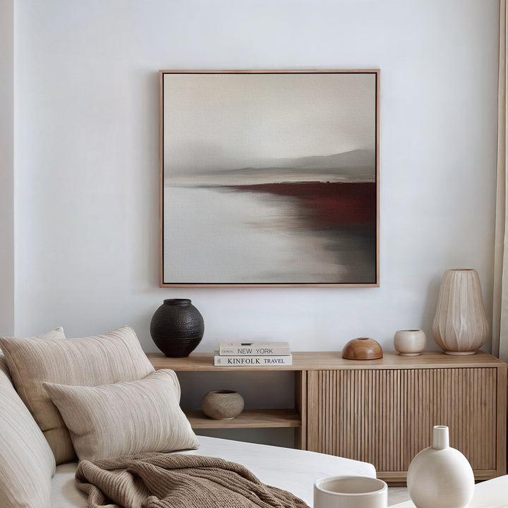 A minimalist living room featuring a beige sofa, neutral pillows, a wooden sideboard with vases and books, and the Fading Light Canvas Art in soft earth tones that elevates the decor.