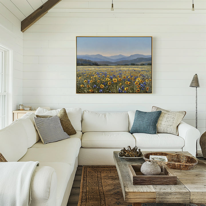 A cozy, bright living room with a white sectional sofa, patterned pillows, a rustic wooden coffee table, and modern decor featuring the Fields of Color Canvas Art on a white shiplap wall.