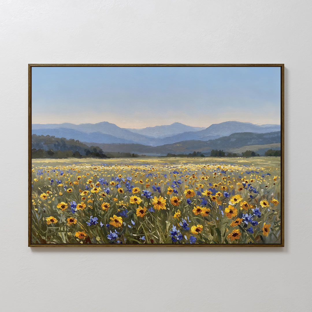 The Fields of Color Canvas Art features a vibrant meadow of yellow and blue wildflowers with rolling hills and mountains, adding modern charm to any room when displayed on a crisp white wall.