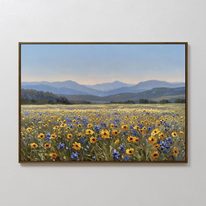 The Fields of Color Canvas Art features a vibrant meadow of yellow and blue wildflowers with rolling hills and mountains, adding modern charm to any room when displayed on a crisp white wall.
