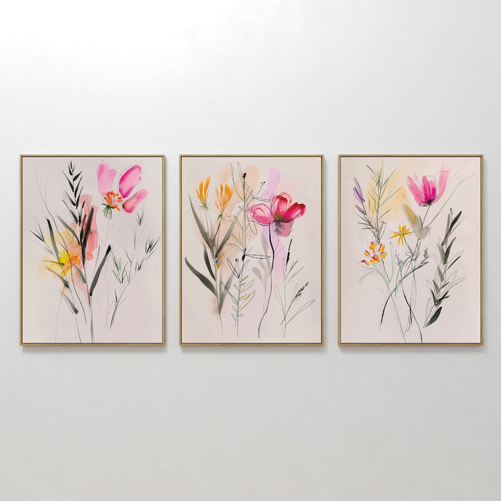 The Floral Harmony Set of 3 features framed watercolor paintings of abstract wildflowers in pink, yellow, and purple on a light background—perfect minimalist wall art to elevate your living room decor.