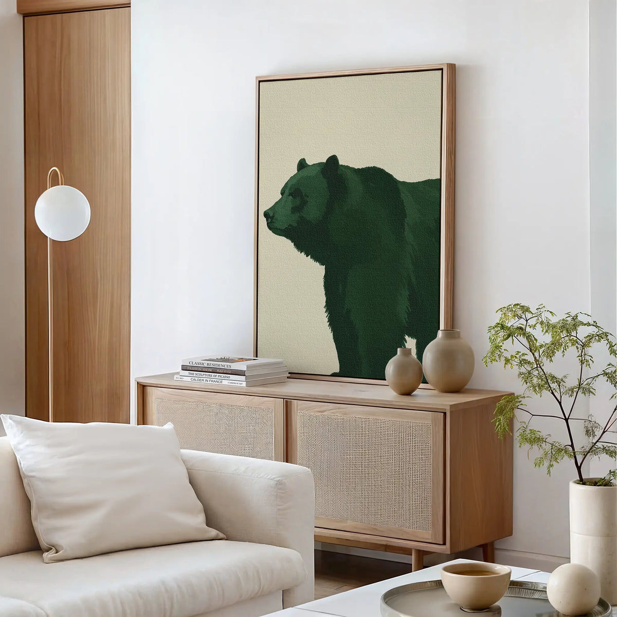 A modern living room with a light sofa, round coffee table, and sideboard topped with books and vases. Above the sideboard hangs the striking Forest Guardian Canvas Art. A potted plant brings a fresh touch to the stylish modern rustic decor.