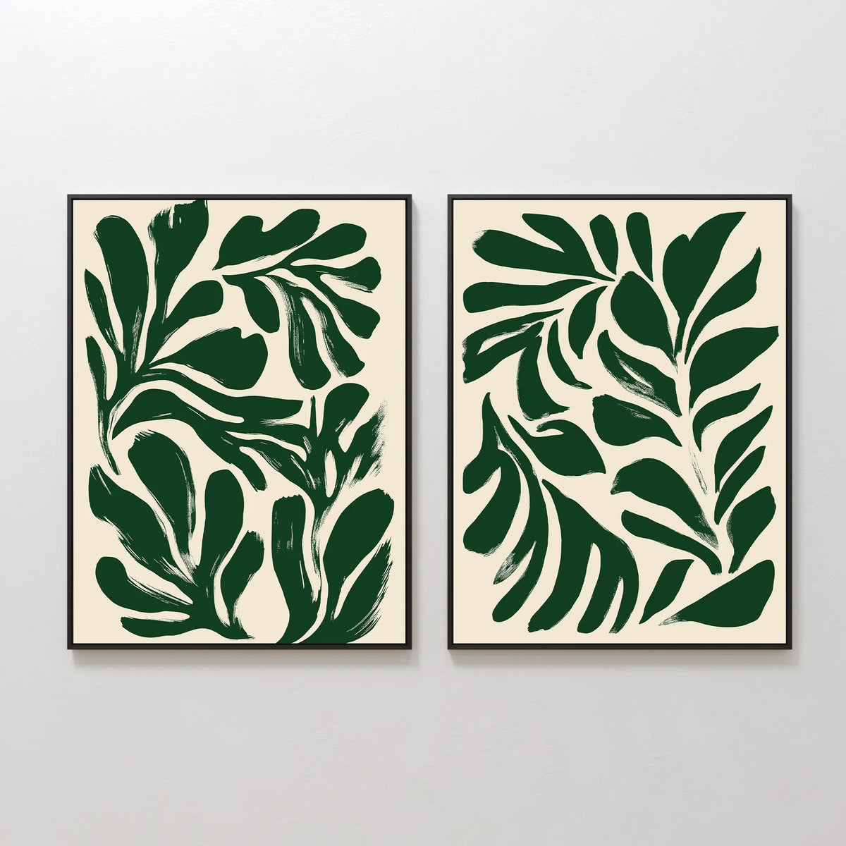 The Forest Leaves Set of 2 features framed abstract art prints with bold, dark green leaf shapes on a cream background, bringing a tranquil, Nordic Park vibe to your space when displayed side by side on a white wall.