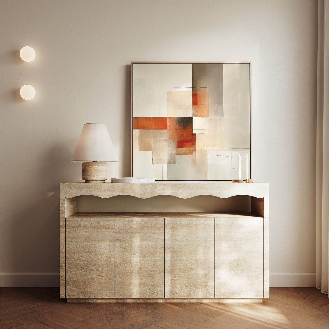 A modern console table with a wavy edge stands against a light wall. On top are a beige lamp and the Fractured Light Canvas Art, with orange, gray, and beige blocks. Two round wall lights and sheer curtains complete the minimalist decor.