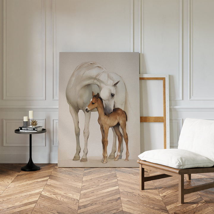 The Gentle Bond Canvas Art, featuring a white horse nuzzling a brown foal, leans against a white-paneled wall, bringing elegant charm to this refined space with herringbone flooring, a cushioned chair, and a round table with candles.