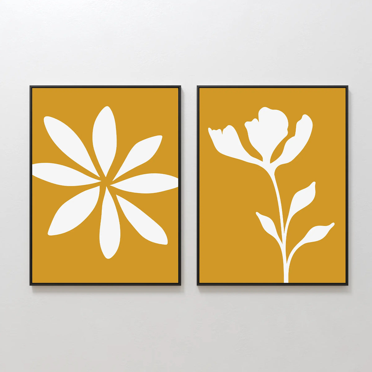 The Golden Bloom Set of 2 features framed minimalist floral prints with white silhouettes on a mustard yellow background, hung side by side to create striking modern wall decor.