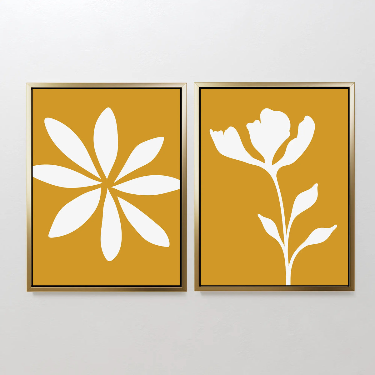 The Golden Bloom Set of 2 includes framed minimalist prints: one with a stylized eight-petal flower and another with a single stem, both featuring white floral silhouettes on mustard yellow—ideal for floral wall art.